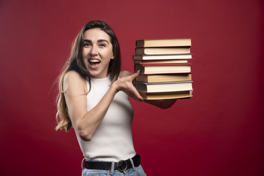 Girl carries a heavy pile of books on a red background