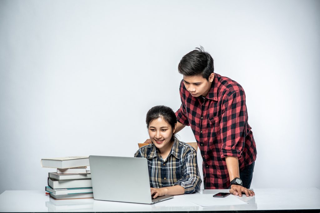 Men teach women how to work with laptops at work